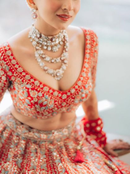 A shot focusing on the stunning craftsmanship of the bridal lehenga and the layered necklace. I pay close attention to the fashion and details you've chosen for your day.