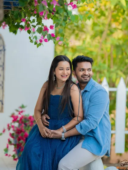 A happy and relaxed moment from Jui and Vaikrant's pre-wedding shoot. The bright flowers and white fence create a charming, picturesque setting.