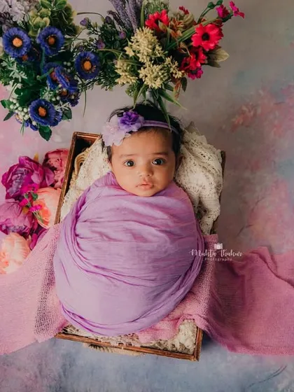 A full view of this little flower, surrounded by shades of purple and pink. This setup is perfect for a baby girl's milestone session.