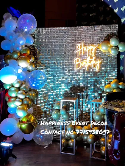 This is another example of a sequin wall backdrop, this time with a silver shimmer effect. The blue and gold balloon garland adds a touch of color and dimension to the setup.
