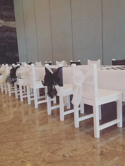 A simple and elegant table setup for a kids' party, with white chairs decorated with black and white bows for a classic look.