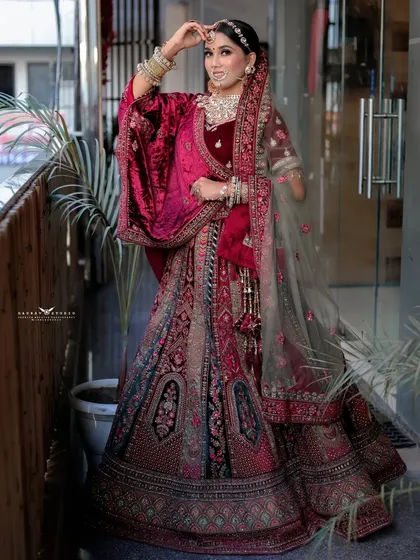 A full-length shot of the bride, showing the magnificent flare of her heavily embroidered velvet lehenga.
