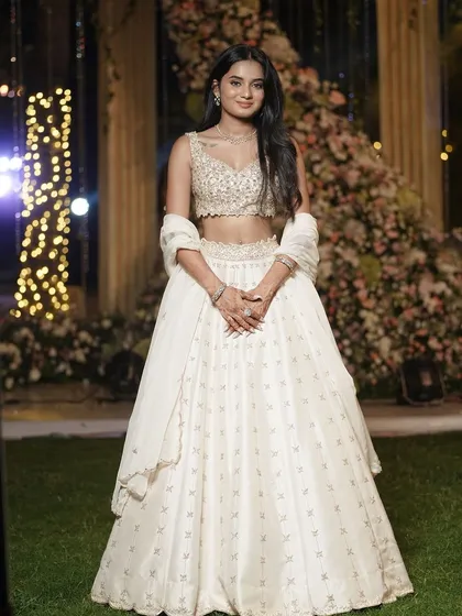 A full-length shot of the client in her ivory lehenga, showcasing its elegant silhouette and subtle sparkle.