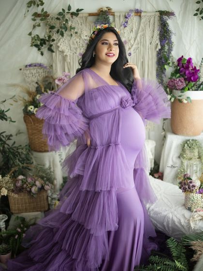 A confident and glowing portrait of a mother-to-be. Her pose and the vibrant purple gown create a striking image in our versatile boho studio.