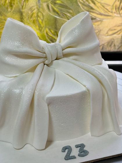 A stunning and elegant cake for a 23rd birthday. The shimmering white fondant bow gives it a luxurious, gift-wrapped appearance.