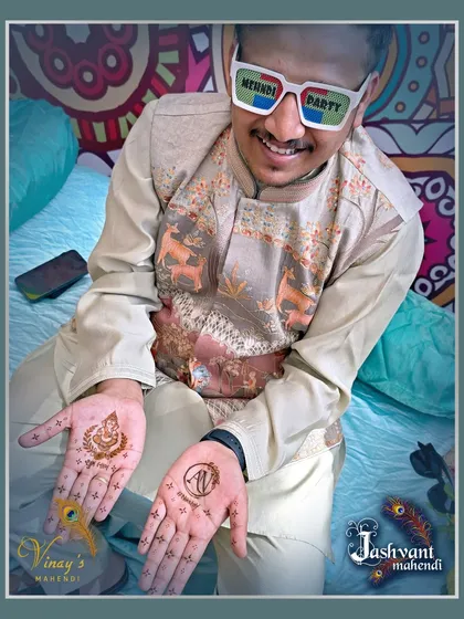 Even the groom can have fun at the mehndi party. This design features a simple Ganesh motif on one palm and a personalized initial 'N' on the other, perfect for a light and festive look.