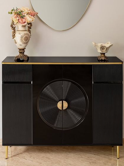 This stunning wooden console and cabinet in black offers a bold, dramatic look. The circular textured detail on the doors and fine gold trim create a sophisticated contrast, making it a perfect storage solution for a modern interior.