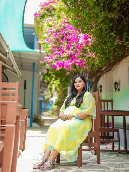 A serene solo portrait of the mother-to-be seated in a beautiful outdoor cafe setting.
