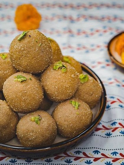 A bowl of our wholesome Atta Laddoos, garnished with pistachios. These are made with whole wheat flour, desi ghee, and nuts.