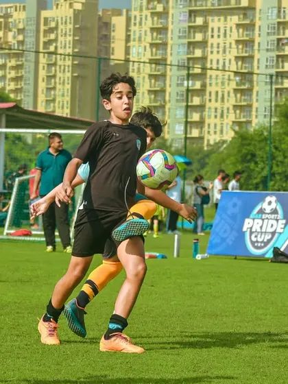 A young player skillfully controls the ball with his chest during a Pride Cup match, a technique taught in our academy.