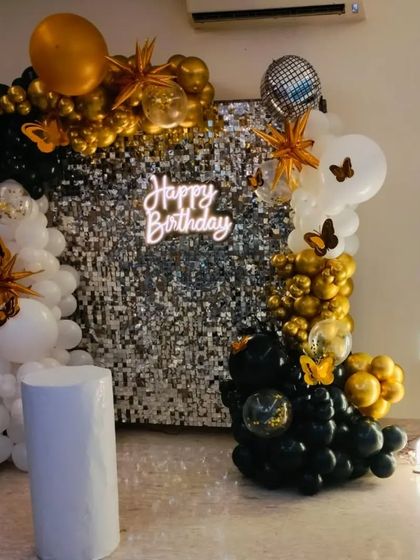 A chic black, white, and gold decoration against a silver sequin wall. This setup includes a 'Happy Birthday' neon sign and a light-up number '2', creating a sophisticated and modern look.