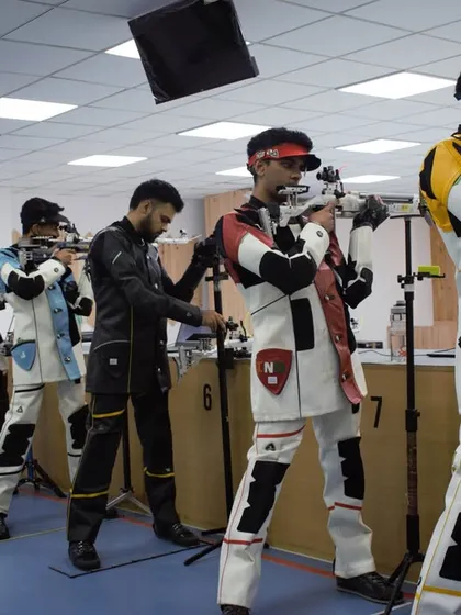 A different perspective of the firing line during a simulated final. Shooters learn to block out distractions and focus solely on their own performance, a key skill for any competitive athlete.