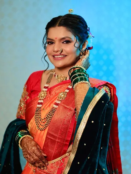 The timeless elegance of a Maharashtrian bride. Her look is perfected with a traditional nath, a bindi, and a radiant makeup look that highlights her beautiful features.
