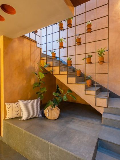 The central staircase is a key feature of the home. I designed a simple metal grid along the staircase, which serves as a trellis for hanging plants, turning a transitional space into a vertical garden.