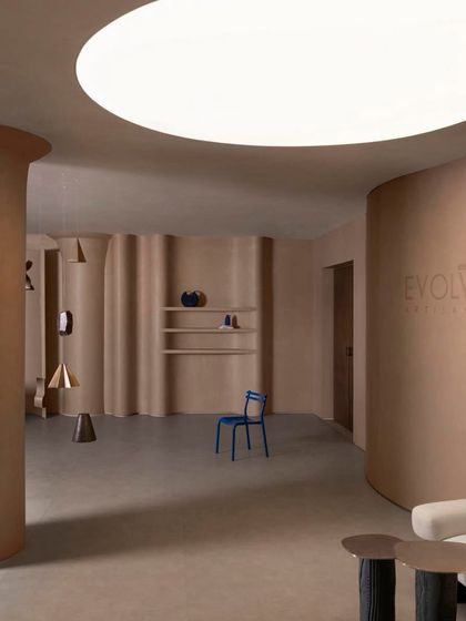 The showroom's open, flexible layout is punctuated by sculptural columns and a large circular ceiling light, creating a versatile and inspiring environment.