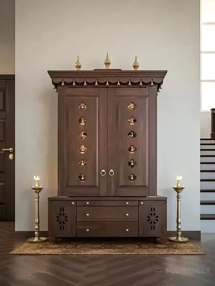 This design showcases a freestanding pooja cabinet with closed doors, ideal for integrating a prayer space into a living or dining area. The doors feature small, bell-shaped cutouts for ventilation and a touch of traditional aesthetics, with ample storage in the base cabinet.