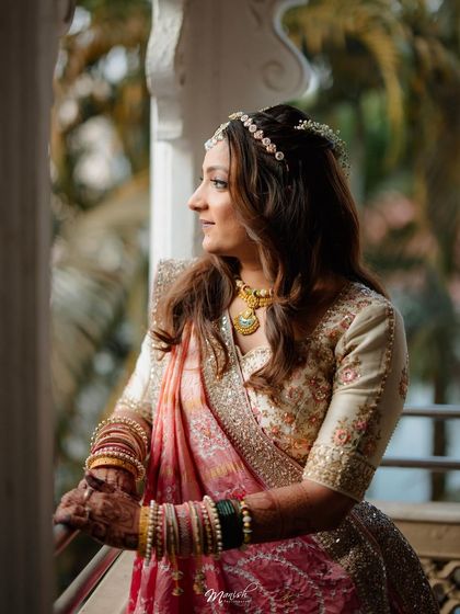 A thoughtful portrait of the bride looking out from a balcony, her traditional jewelry and attire looking stunning in the natural light.