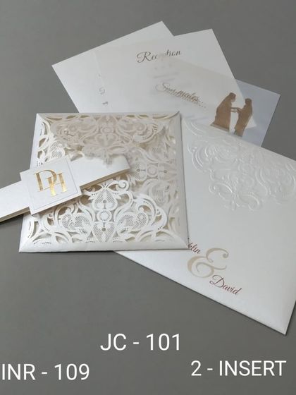 This elegant white invitation features an intricate laser-cut damask pattern on the cover. A custom monogrammed band holds the card together, and it includes inserts for your event details.