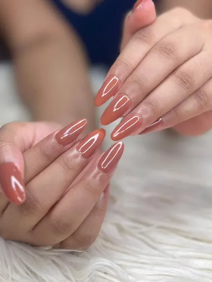 A look at a perfectly executed set of long, almond-shaped nail extensions with a glossy, solid terracotta gel polish. This shows the flawless finish and shape I can achieve for a clean and elegant style.