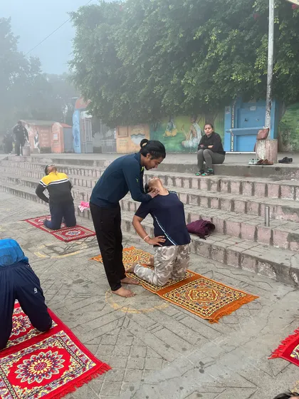 Providing a gentle adjustment in Ustrasana (camel pose) during our Haridwar yoga session to ensure proper alignment.