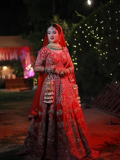 A full-length shot of my bride, looking absolutely regal in her red lehenga against the beautifully lit backdrop.