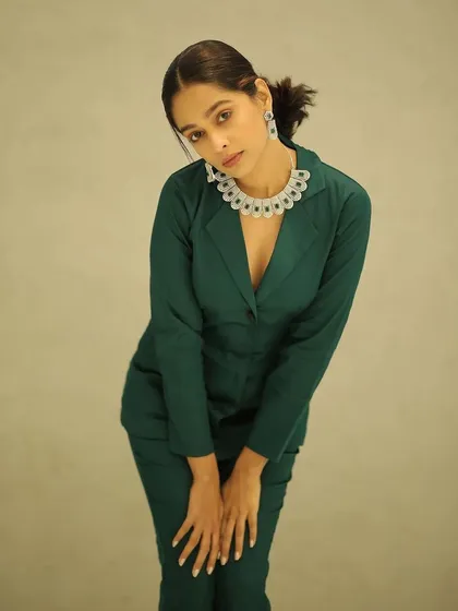 A full look of the sophisticated styling for Mugdha Chaphekar. The combination of the sleek ponytail, natural makeup, and tailored suit creates a very polished and professional image.