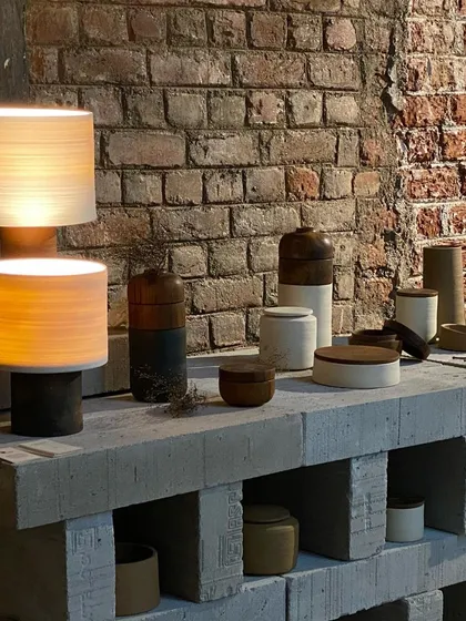 Ceramic lamps and vessels from the 'Intersection' exhibit we curated. The display is set against a raw brick wall, highlighting the contrast between industrial space and handcrafted objects.
