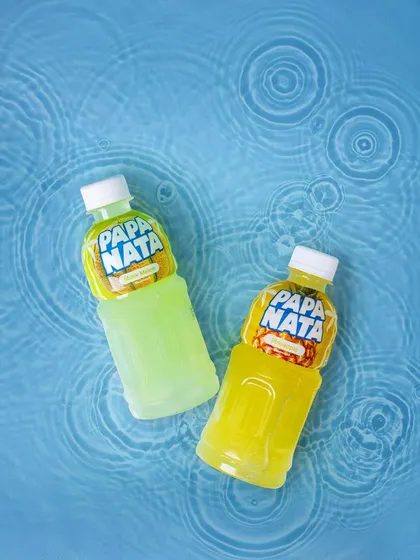 A creative flat lay of Papa Nata juice bottles in water with ripple effects. This dynamic shot evokes a sense of refreshment and is perfect for social media campaigns for beverage brands.