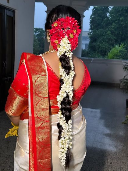 A back view of the traditional South Indian bridal braid, showing the full length and the beautiful floral arrangement at the top.
