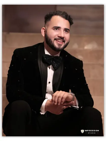 A handsome portrait of the groom, Prabhat, looking dapper in his tuxedo and bow tie, seated on the stairs with a relaxed smile.