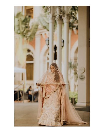 The bride, Aaisha, looking ethereal in her pastel lehenga and veil, captured in a moment of quiet grace.