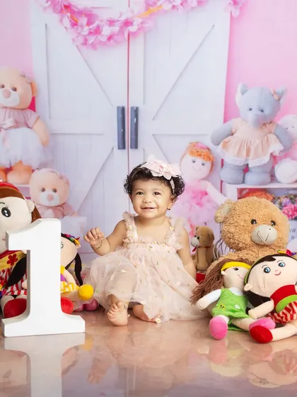 A happy smile from the birthday girl, sitting proudly next to the number one. This is a classic first birthday portrait.