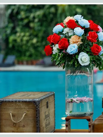 A poolside setup featuring a rustic wooden chest and a tall vase of colorful roses, demonstrating how we tailor our decor to complement any venue.