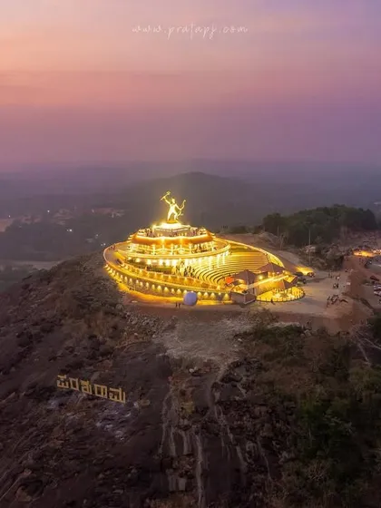 The magnificent Shri Parashurama Theme Park near Udupi, illuminated at dusk. This aerial view showcases the grand scale of the 33ft bronze sculpture and the surrounding amphitheater.