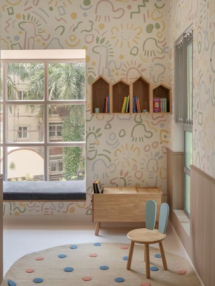 A quiet reading nook with a window seat, house-shaped bookshelves, and playful wallpaper. These small, thoughtful spaces scattered throughout the school provide children with a place to pause and have a moment to themselves.