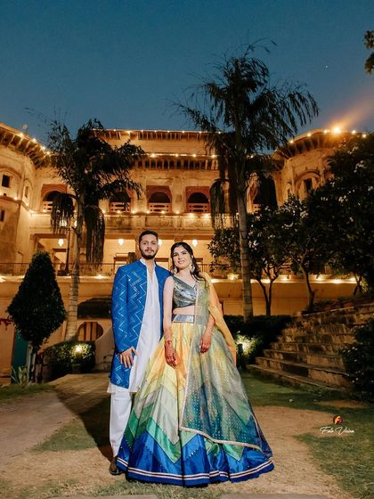 A stunning evening portrait of the couple at Neemrana Fort, with the beautifully lit heritage property creating a magical and royal backdrop.