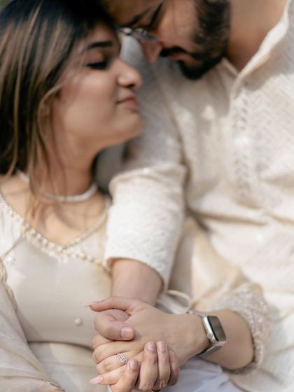 A close-up on the couple's hands, a subtle but powerful symbol of their connection, set against the soft-focus background of a park.