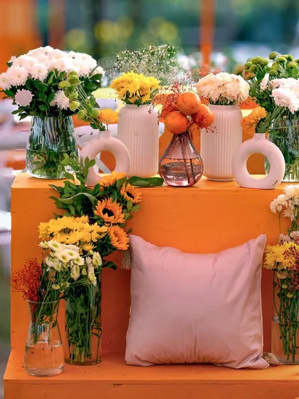 A close-up of the floral arrangements for the 'Love in Mexico' theme, featuring bright yellow and white flowers in modern ceramic vases against a bold orange block.
