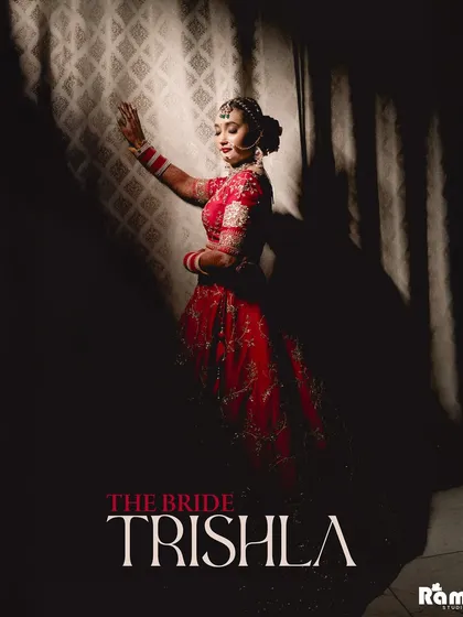 An artistic and dramatic portrait of the bride, "Trishla." The use of shadow and light creates a powerful silhouette, highlighting her pose and adding a touch of mystery and elegance to her bridal look.