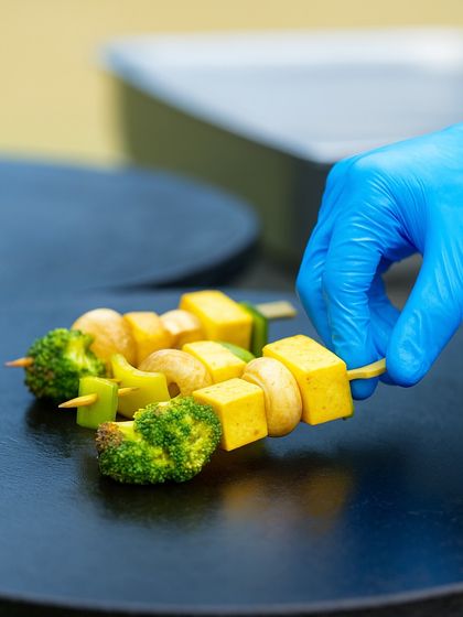 A chef prepares a vegetable and paneer skewer on the grill. Our live cooking stations are an interactive part of our celebration brunches, adding to the festive atmosphere.