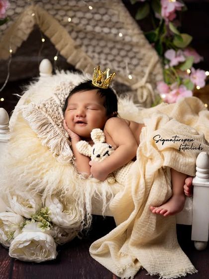A smiling newborn princess in her royal cot, a precious and rare capture of a sleepy smile.