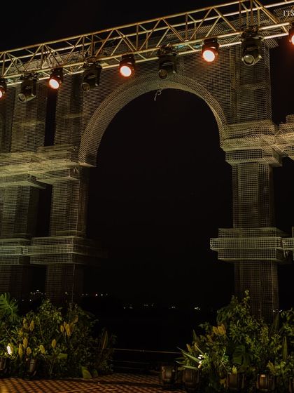 The main stage entrance at night, where the grand mesh arch is lit to create a dramatic and awe-inspiring focal point.