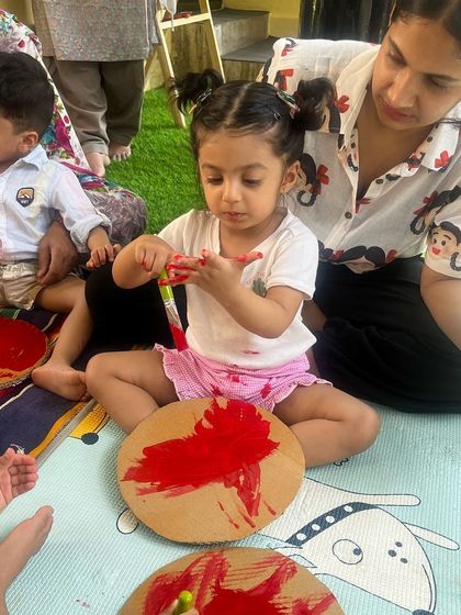 Guided by a parent, this little artist is fully engaged in her painting. These shared moments of creativity are at the heart of what we do.