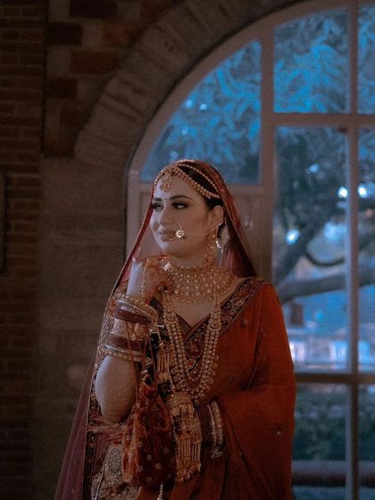 A stunning portrait of the bride, Nisha, by a window, the natural light beautifully illuminating her features and her regal attire.