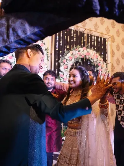 A fun, candid moment on the dance floor. The couple is surrounded by their friends, all sharing a laugh and a dance, perfectly capturing the high-energy spirit of the Sangeet.