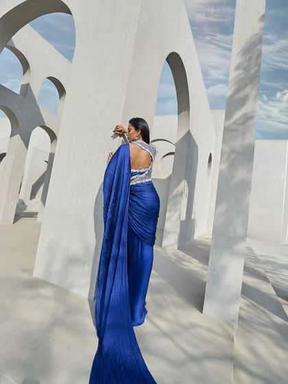 The back view of the active blue pre-draped sari, showcasing the pearl-embellished back and the dramatic flow of the crushed fabric.