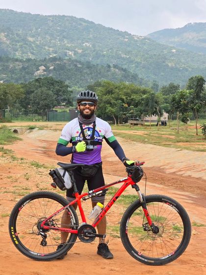A rider proudly posing with his mountain bike against a hilly backdrop during the Rajyotsava 200k. Our events are open to all types of bicycles.