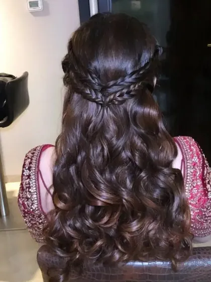 A romantic half-up hairstyle featuring two crossing braids and soft, flowing waves. This is a beautiful and intricate look for a Sangeet or engagement.