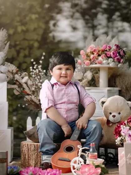 A happy portrait of a three-year-old boy in a beautiful, festive outdoor setting. His smile is bright and genuine, surrounded by his furry friends.
