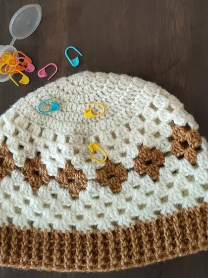 This is my Diamond Granny hat, which combines the classic granny stitch with a diamond colorwork pattern. The stitch markers show how I keep track of my rounds, a handy tip I share in my classes.